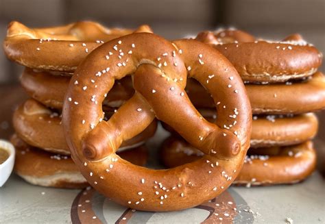 Pretzel twister - 1) Twists round strips of dough to form into pretzels: Picks piece of dough from conveyor and holds one end between thumb and forefinger of each hand. 2) Flips dough into loop, and crosses and presses ends to outer circumference.